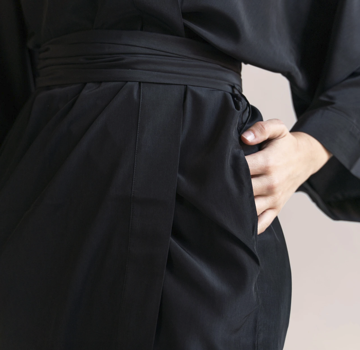 Close-up of the black version of the robe, with the model's hand casually tucked into the pocket.