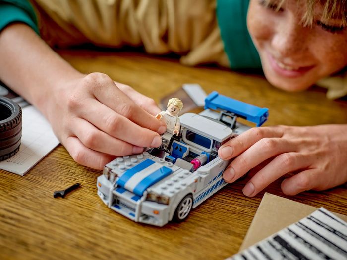 A child enjoys playing with a Lego car set.