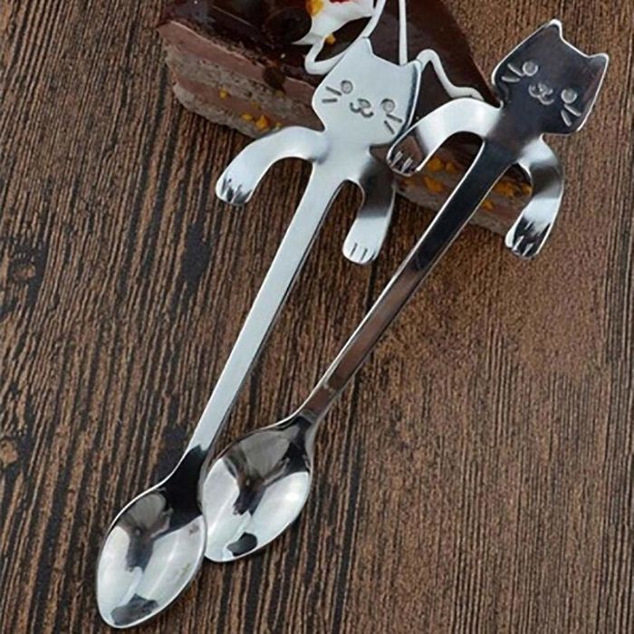 Two cat-shaped spoons resting on a wooden table.