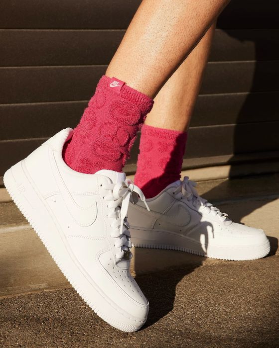 A model wearing white Nike Air Force 1 sneakers.