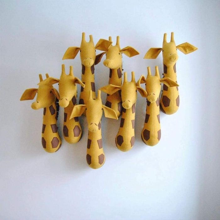 Multiple stuffed giraffe heads mounted together on a wall