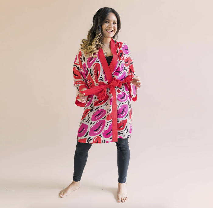 A model rocking the Nuno robe, featuring a playful pattern of pink and red lips, with red trim and a matching red waist tie.