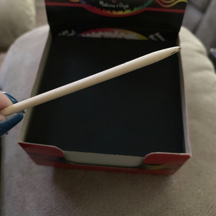 A close-up of the wooden stylus included with the box of bright sticky notes for creating scratch art.