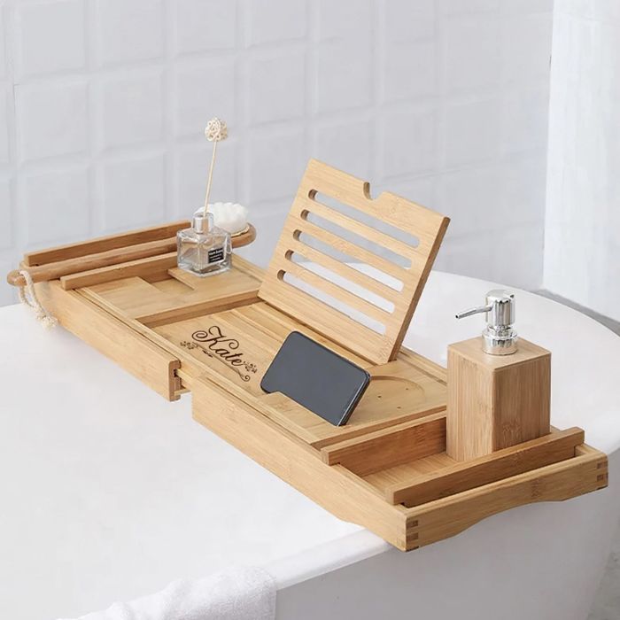 The bamboo tray resting on a tub, engraved with 'Kate' and holding a phone, brushes, and soap