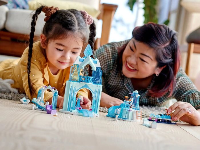 A child and parent enjoy playing with a Frozen Lego set together.