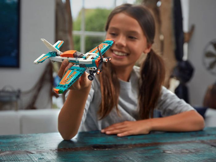 A child plays with a Lego set of a plane they've built.