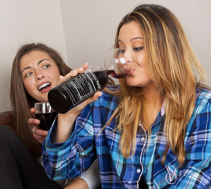 A model drinking from a bottomless wine glass, which is designed to resemble a wine bottle at the base. The 'neck' of the bottle is actually the stem of the wine glass.