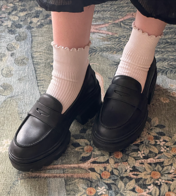 A writer's black loafers paired with thick soles and white ribbed socks
