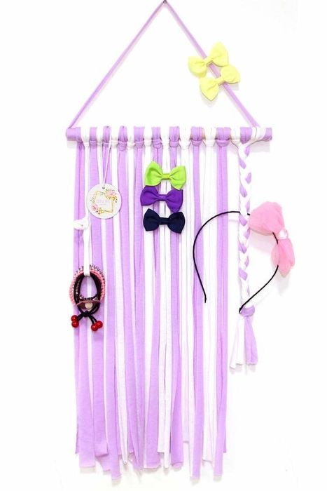 a purple and white fringed banner holding hair ties, bows, and a headband