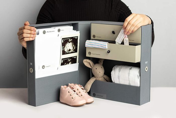 An open box featuring compartments for important documents, shelves for storing small dolls and clothes, and labeled sections