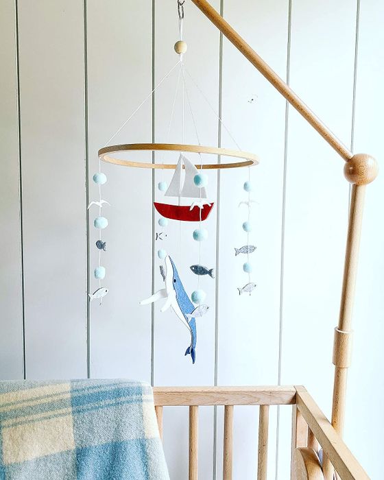 A mobile made of felt and wood featuring fish, a whale, and a sailboat