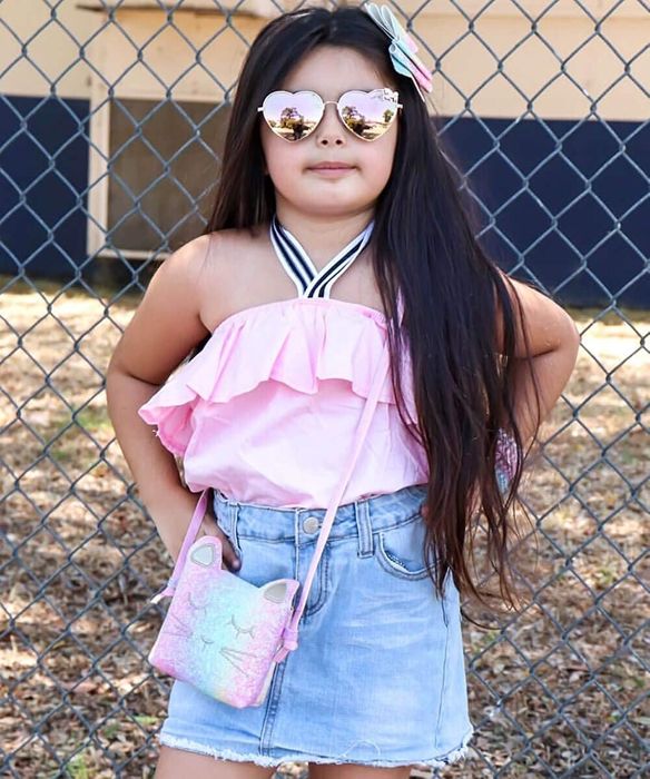a child model posing with the pastel rainbow glitter version of the bag