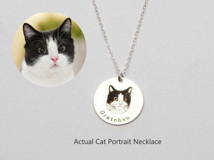 A silver necklace with a cat portrait displayed beside a photo of the cat, Gretchen