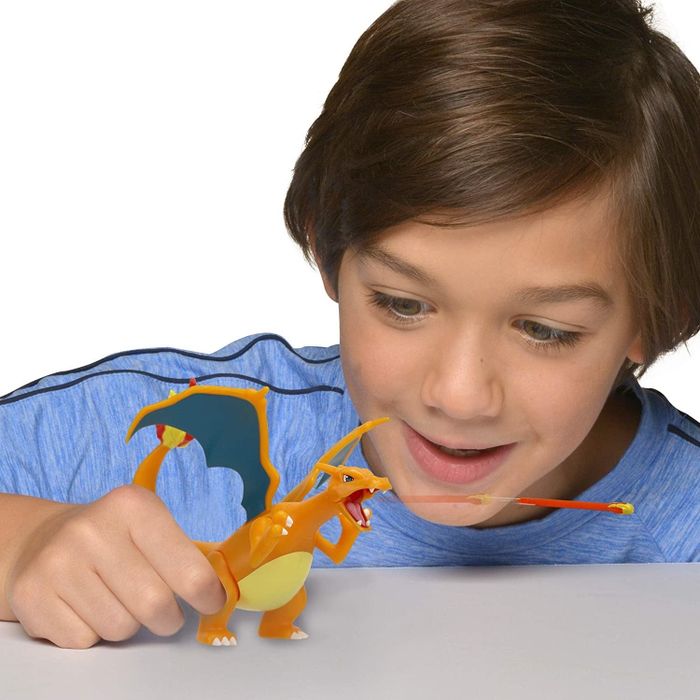 a child playing with the Charizard figure as it shoots a fireball
