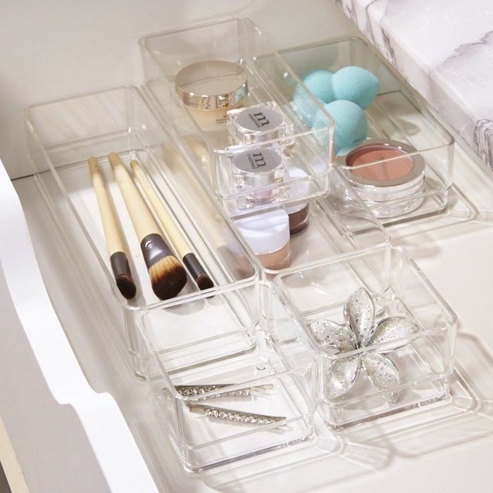 the clear acrylic vanity trays in square and rectangular shapes, holding jewelry, bejeweled tweezers, makeup brushes, and other small items