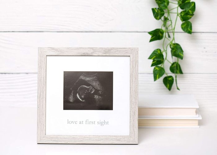 A rustic frame holding a sonogram with the phrase 'love at first sight' inscribed at the bottom