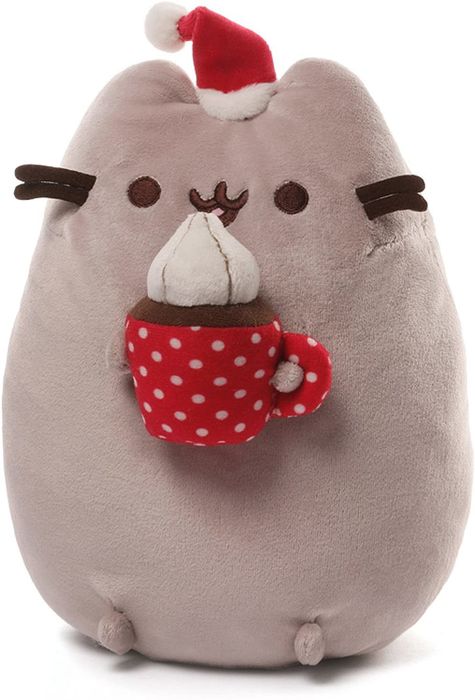 a plush Pusheen wearing a Santa hat and holding a mug of hot cocoa topped with whipped cream