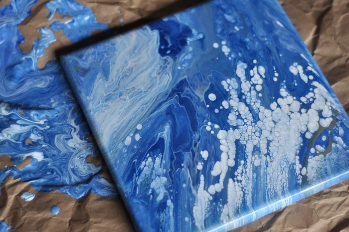 A square canvas featuring a blue and white drip painting