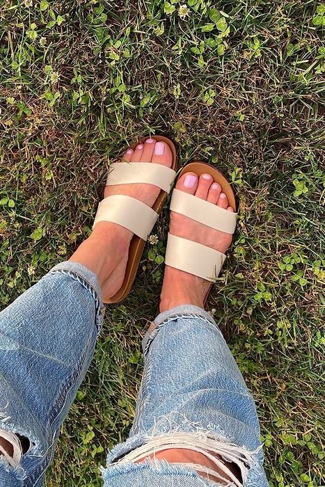 A reviewer’s photo of a person wearing ripped jeans and tan sandals, standing on grass.