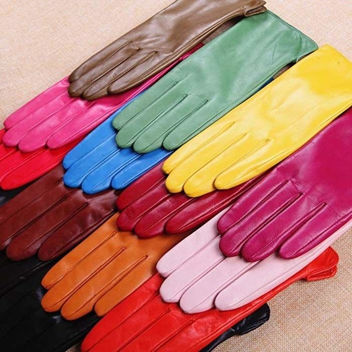 A variety of gloves in different colors, including orange, pink, fuchsia, red, black, burgundy, yellow, blue, and brown, stacked neatly on top of each other.
