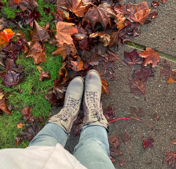 reviewer wearing the boots with autumn leaves scattered at their feet