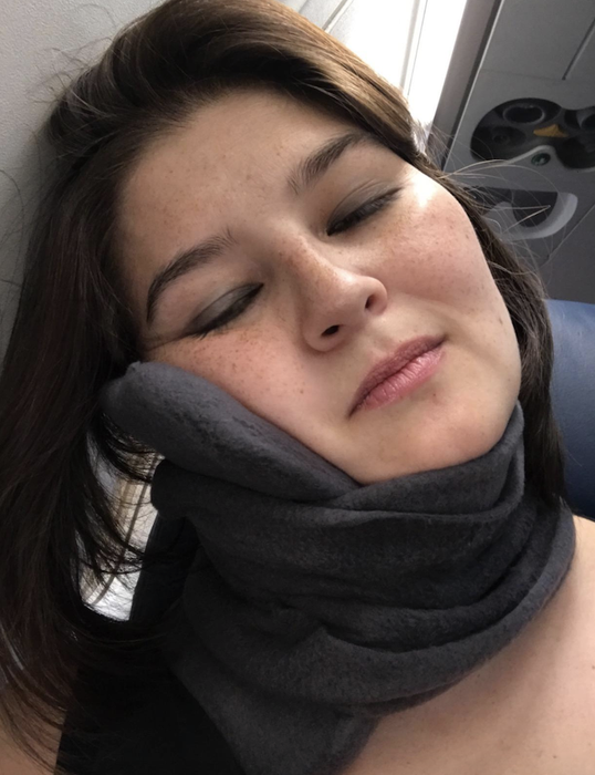 Another reviewer enjoys the comfort of the scarf wrapped around their neck as they rest their head against the window seat. Lucky them — a window seat and this pillow-scarf combo!