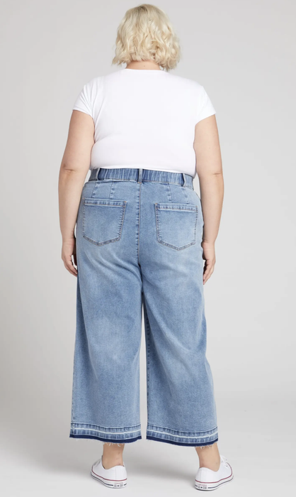 Model presenting the rear view of the product paired with a white t-shirt and sneakers.