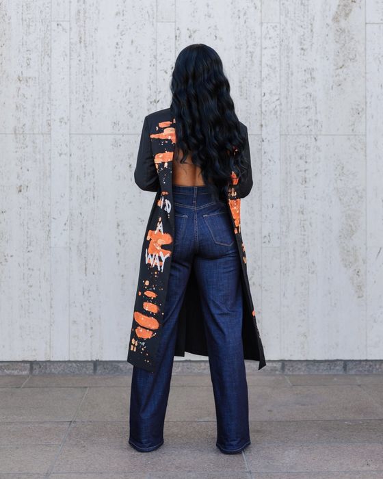 A model showing the back view of the product in front of a white speckled wall.