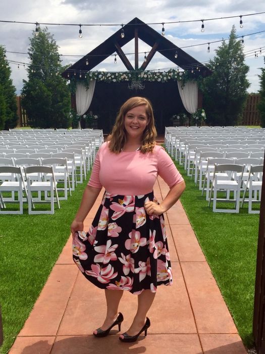 a reviewer wearing the dress featuring a pink top and a blue/pink floral skirt