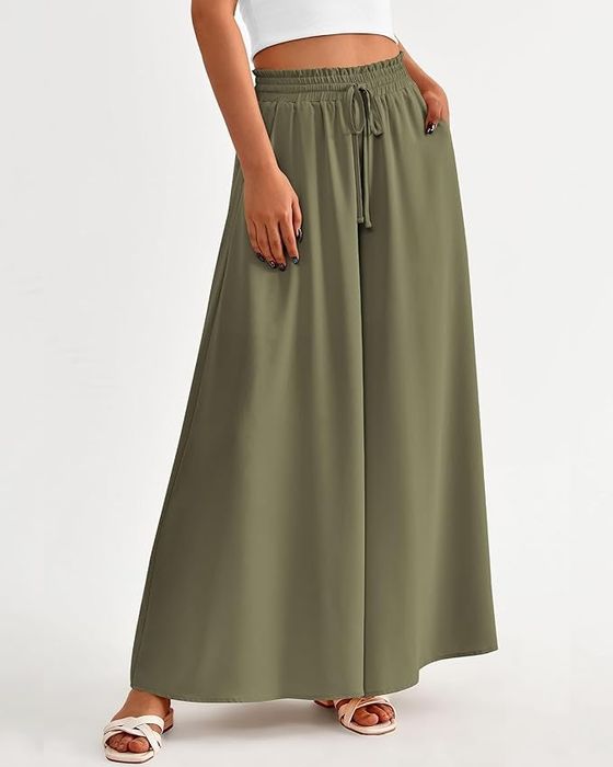 Person styling wide-leg green pants and sandals, posing casually with one hand on their hip
