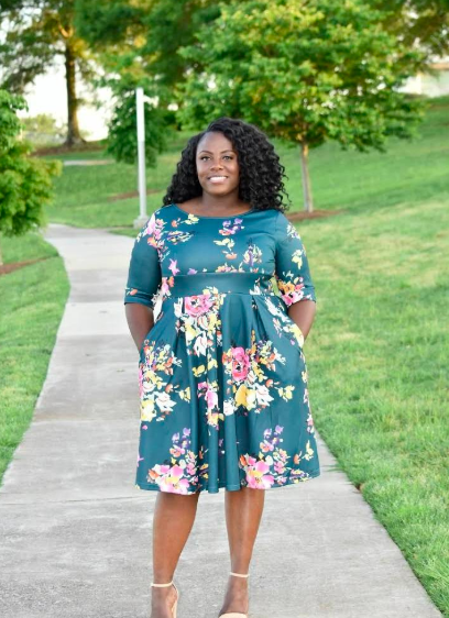 a reviewer wearing the teal boat neck 3/4-sleeve dress adorned with pink and green flowers