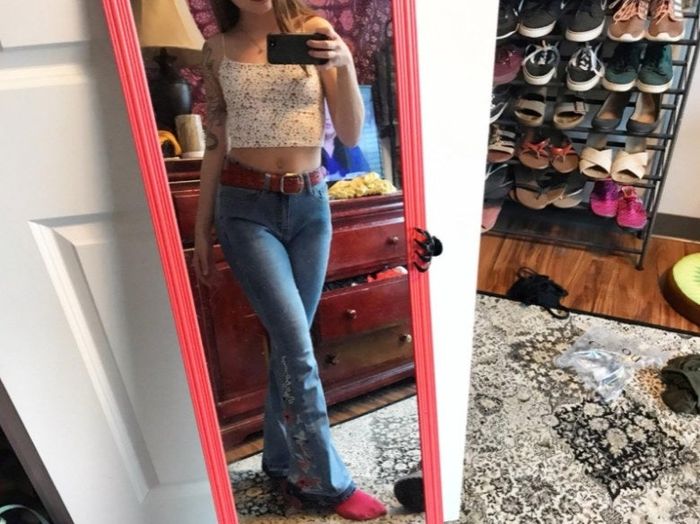 a reviewer modeling the jeans with a belt