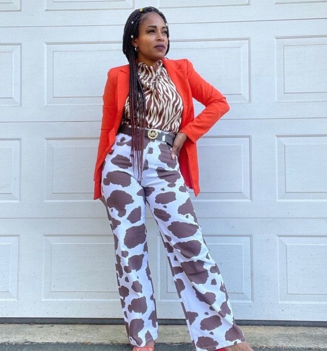 a reviewer wearing the brown and white cow-print pants