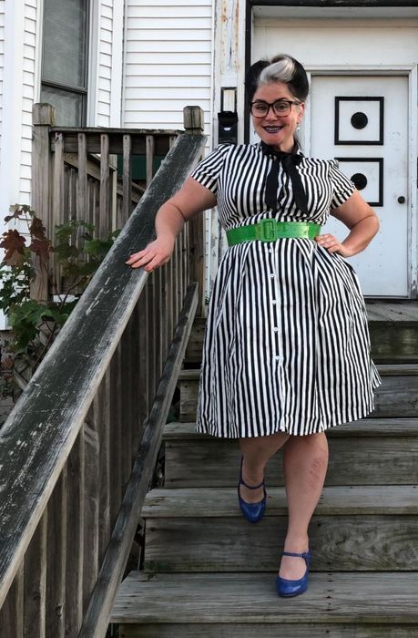 Reviewer modeling the knee-length short-sleeved dress featuring black and white vertical stripes