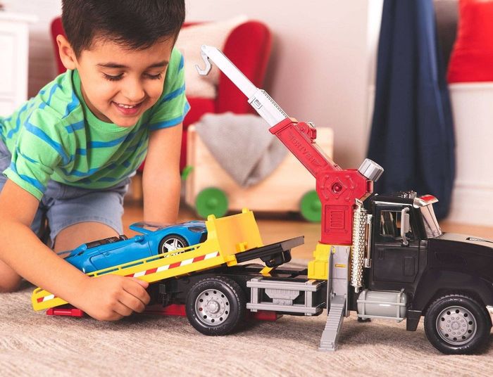 Child playing with a crane truck and toy car