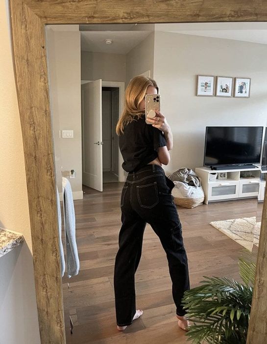 a reviewer wearing the black jeans with white stitching