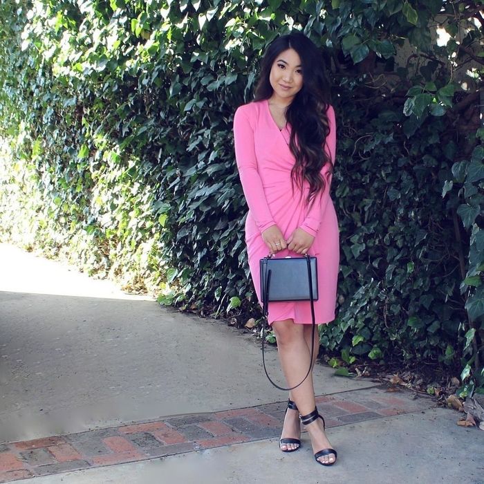 Reviewer modeling the bright pink long-sleeved wrap dress.