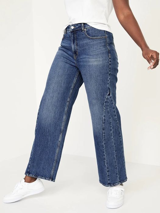 Model stepping forward, showcasing dark blue wide-leg jeans with intricate stitching details.