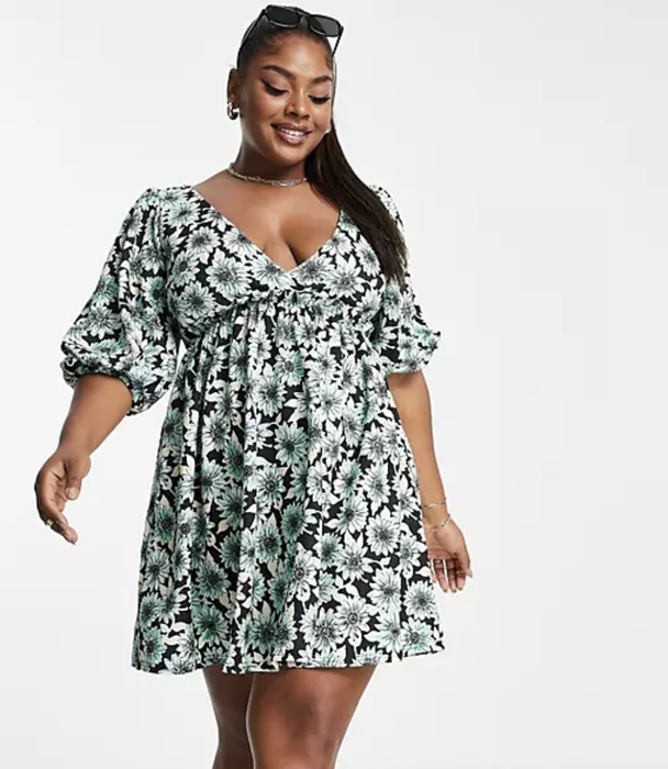 model wearing the dress featuring a black, white, and teal floral print