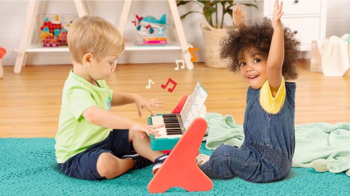Two kids playing on a small piano