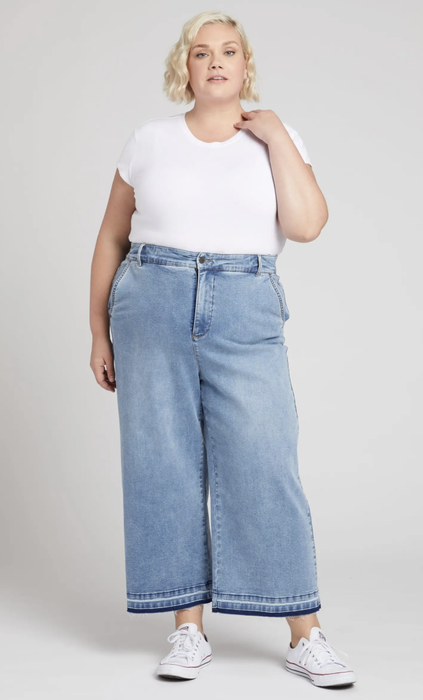 Model showcasing light wash, high-rise, wide-leg jeans with a contrasting hem detail.