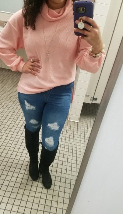 A reviewer modeling the jeggings paired with boots and a sweater