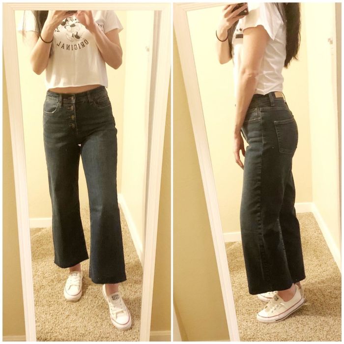 A reviewer showcasing both the front and side profiles of dark wash, button-front, wide-leg jeans.