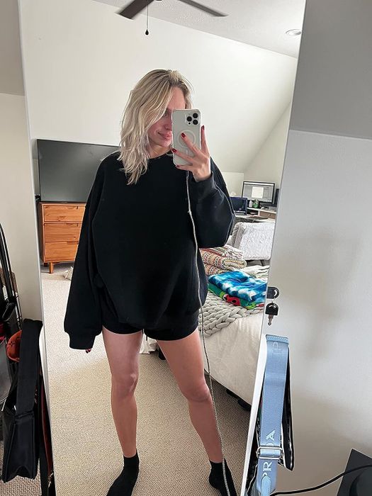 A reviewer modeling a black oversized sweatshirt