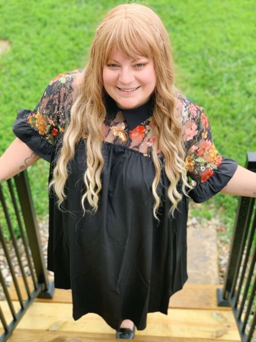 Reviewer sporting the black dress featuring a collar, sheer floral yoke, and ruffled short sleeves