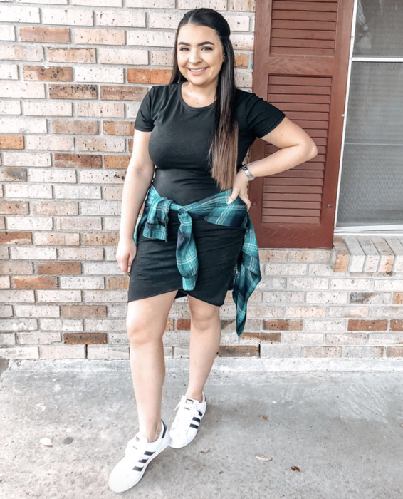 The reviewer is dressed in a black dress paired with sneakers.