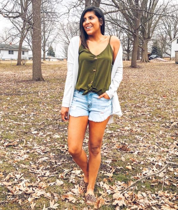 A reviewer rocking a button-up green tank, styled with denim shorts and a white cardigan