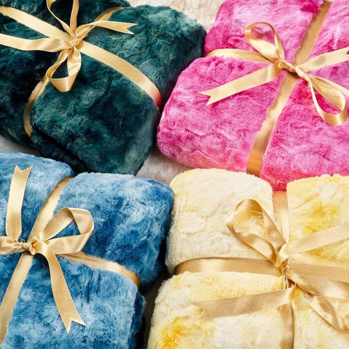 The green, pink, blue, and yellow blankets neatly folded and tied with bows, ready for gifting