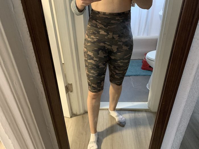 A reviewer showcasing camo biker shorts.