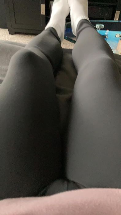 A person seated with legs stretched out, dressed in black leggings and white socks